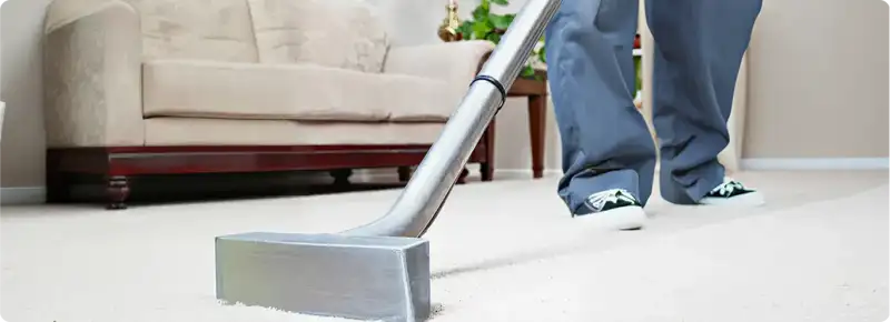 Carpet cleaning technician using a hot-water extraction wand on a light-colored carpet in a living room, Knoxville, TN.